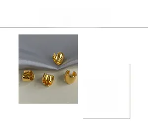 Detail of four gold geometric ear cuffs with a high-shine polished metallic finish