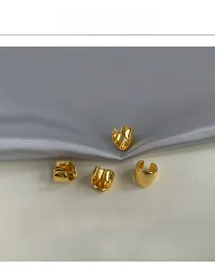 Set of four minimalist gold-plated ear cuffs with high-polish finish on silk background