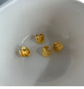 Macro view of gold-plated non-pierced ear cuffs with smooth C-shaped metallic design