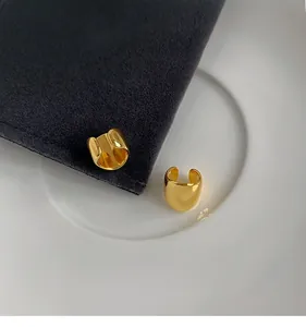 Detail of high-polish gold wide C-shape ear cuffs on velvet display for non-pierced ears