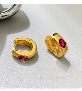 Macro shot of French vintage gold hoops featuring inlaid red oval zircon gemstones