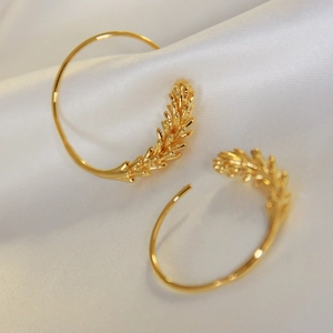 Elegant gold brass geometric wheat spike earrings on white satin fabric background