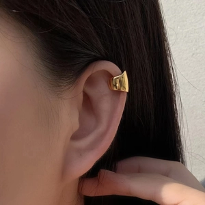Polished gold ear cuff on female model without ear piercing, minimalist retro style