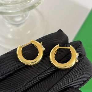 Macro detail of gold-plated hoop earrings with baguette-cut zircon inlay and sleek finish