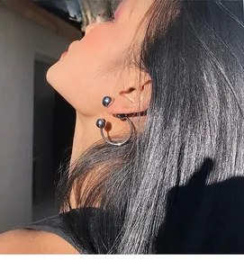 Silver metal C-shaped bead earrings worn by a model for a chic industrial look