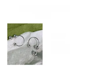 Macro shot of silver sphere drop earrings with C-shaped hooks on a textured background