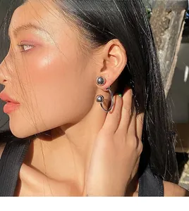 Macro detail of minimalist silver ball C-shaped earrings worn on an Asian model's ear