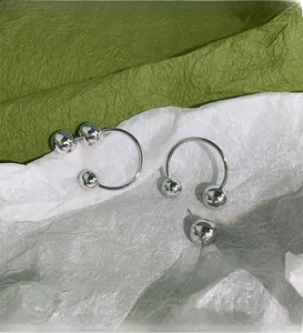Artistic close-up of polished silver sphere earrings on textured green and white paper