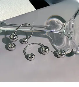 Polished silver sphere earrings set shown in a minimalist display with glass props