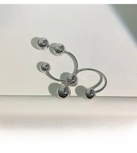 Detailed close-up of U-shaped silver ball earrings with high-polished metal finish