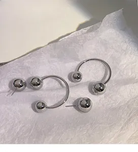 Close-up of polished silver sphere earrings with removable jacket design on white paper