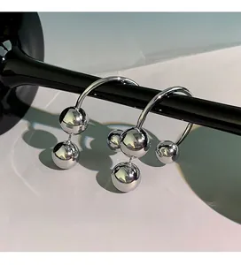 Artistic detail of silver ball drop earrings with three polished spheres on curved rods
