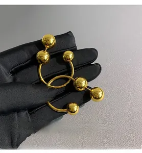 Detailed view of polished golden spheres design earring held against a black glove