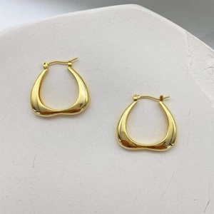 Elegant gold-tone geometric heart-shaped hoop earrings on natural stone background