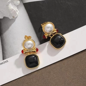 Macro detail of French vintage earrings with pearls, red beads and black square pendants