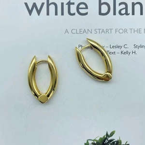 Minimalist gold brass U-shaped hoop earrings on a modern white magazine background