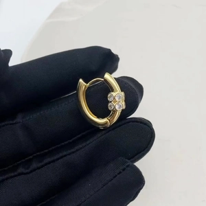 Boucles d'oreilles en U dorées avec accents en diamant sur fond blanc pur