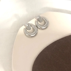 Details von silbernen geometrischen Creolen mit poliertem Spiegel-Finish auf Tablett