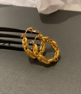 Macro view of gold pig nose chain link hoop earrings with a polished metallic finish