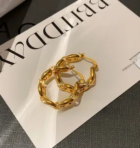 Macro view of gold pig nose chain link earrings on a white birthday greeting card