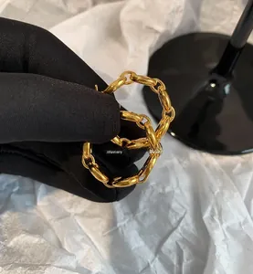 Detailed close-up of chunky gold pig nose chain earrings with a polished metallic finish