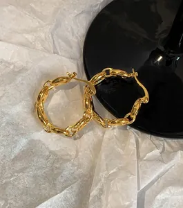Macro shot of gold link chain hoop earrings on a minimalist black and white background