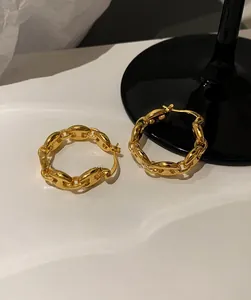 Detailed close-up of golden link chain earrings on a decorative minimalist tray