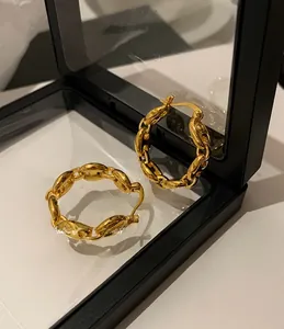 Macro detail of high-shine gold chain hoop earrings in a pig nose link design