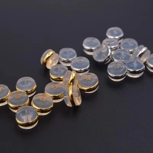 Macro shot of gold and silver silicone earring backs for jewelry making on dark background
