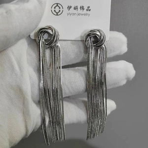Close-up of silver tassel earrings with metal knot design and snake chain fringes
