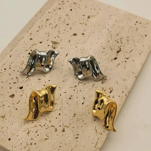 Modern 18K gold and silver plated fluid wave stud earrings set on a travertine stone