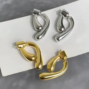 Detail of cross-style teardrop earrings in polished gold and silver metallic finishes