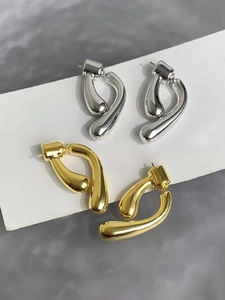 Detail of high-polished gold and silver plated metal drop earrings on a white card
