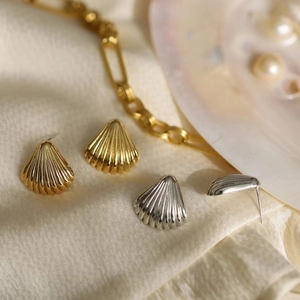 Elegant 18K gold and silver shell earrings on silk fabric with pearl accents