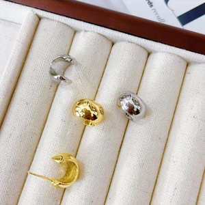 Polished C-shape gold and silver stud earrings displayed on a velvet jewelry tray