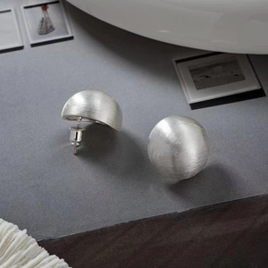 Detailed view of silver dome earrings with a brushed metal finish and sleek modern design