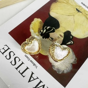 Boucles d'oreilles cœur vintage dorées avec texture martelée et effet nacre sur livre