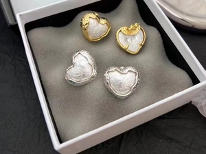 Détail de boucles d'oreilles cœur vintage avec bordure texturée et perle en coffret