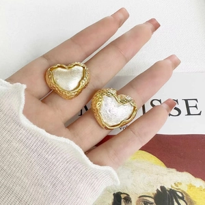 Détail de boucles d'oreilles vintage en cœur doré avec bords martelés et incrustation nacre
