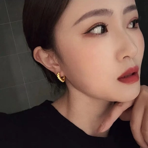 French retro gold-plated twisted heart hoop earrings worn by a model in a close-up