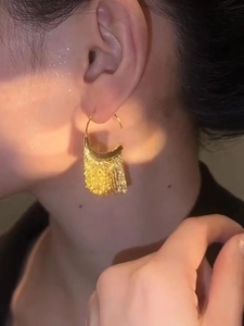 Close-up of golden tassel ear hooks showing the elegant metallic fringe and C-shaped design