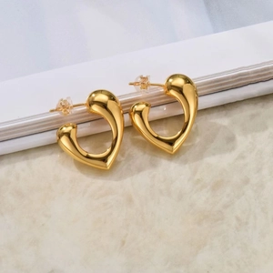 Macro view of gold geometric heart stud earrings with a polished mirror finish surface