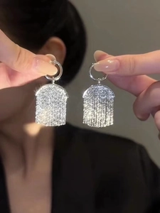 Close-up of sparkling silver tassel earrings with micro-pave rhinestones and fine chains