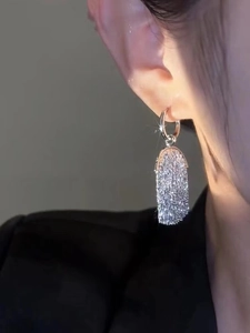 Close-up of silver hoop earrings with shimmering long oval sequins on model