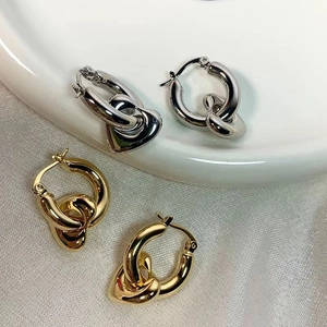 Polished gold and silver heart drop earrings displayed on a white ceramic tray