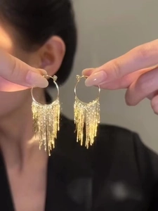 Detailed close-up of golden metal tassel earrings with dangling long chains