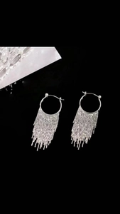 Detail view of long silver metallic tassel earrings with circular hoop and sleek finish