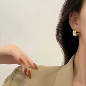 Detail of French vintage gold C-shape earrings with textured accordion pleat finish