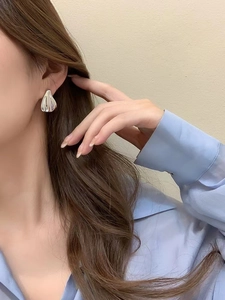 Close-up of minimalist silver metallic teardrop stud earrings worn by a female model