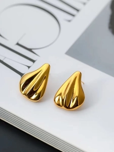 Detail shot of golden fluid teardrop earrings with textured vertical ridges on magazine